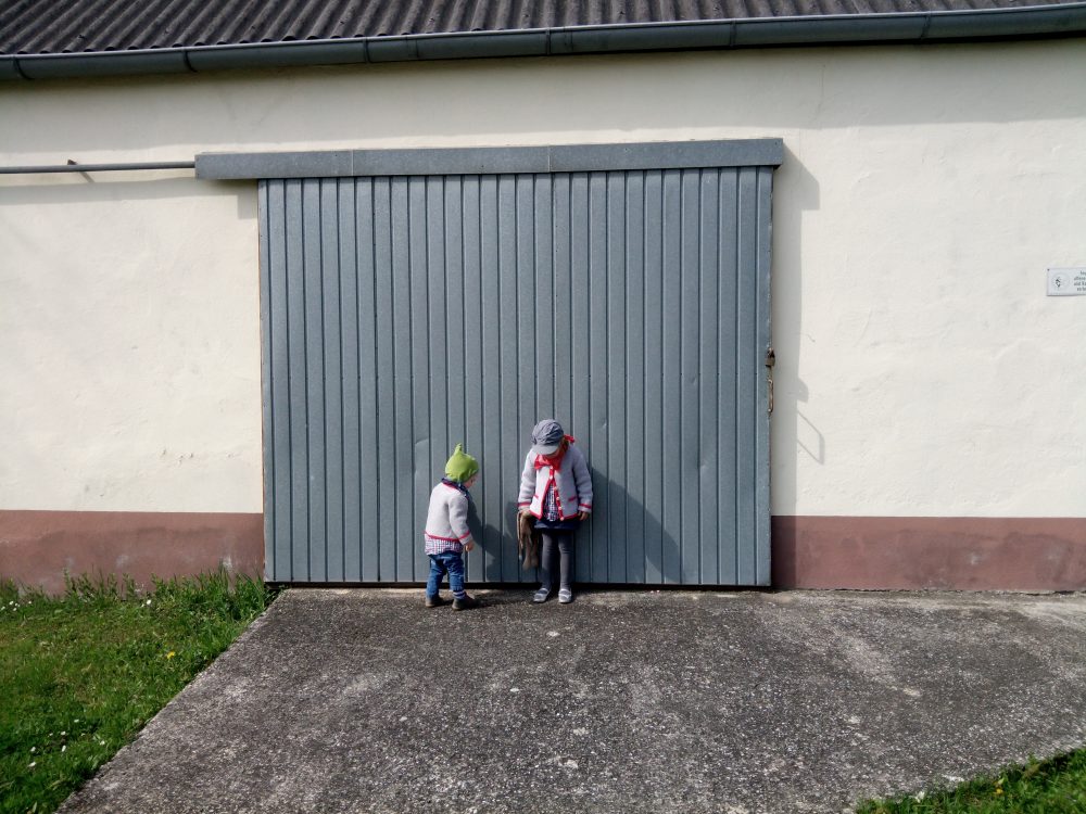 bub und mädchen vor garagentor zum thema rabenmutter